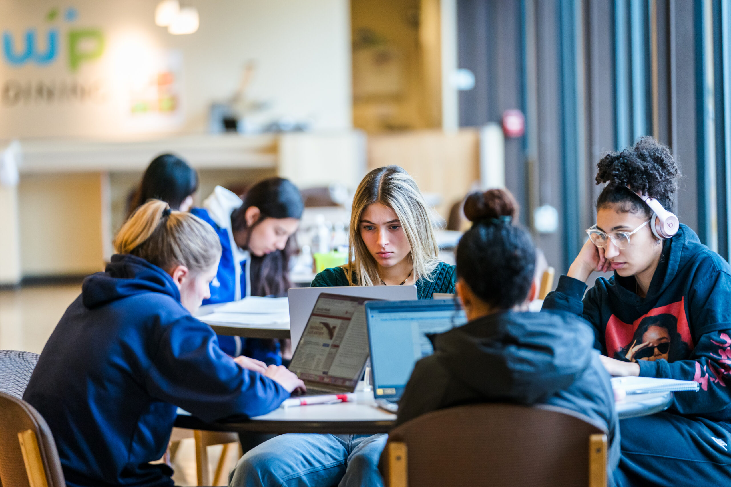 Students sitting at a table looking at their laptops.