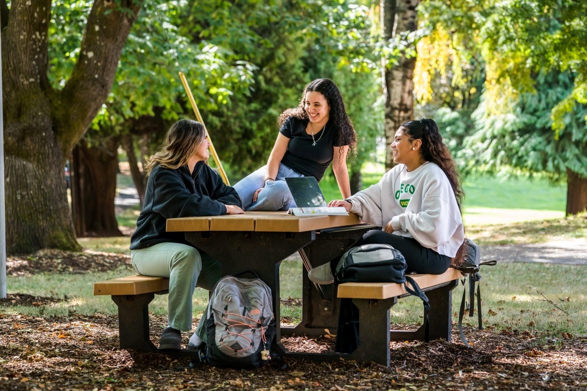 Three students studying at a picnic table outside on the WPU campus.