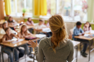 A teacher talks to a classroom of seated students.