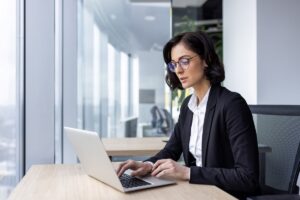 A businessperson works on a laptop in an office.