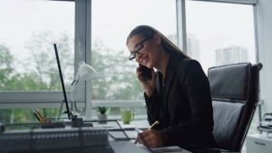 A financial analyst in her office speaks with a client on the phone.