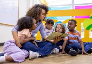 A reading interventionist reads a book to a group of young students in a classroom.